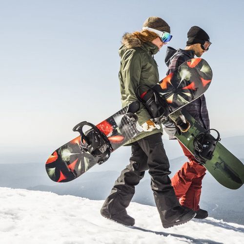 Two snowboarders carrying their boards