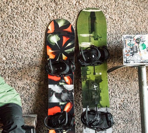 Two snowboards of different lengths lean up against a wall