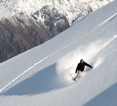 A snowboarder riding powder on a mountainside